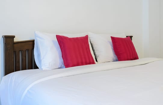White bedroom with tidy King size bed and red pillows