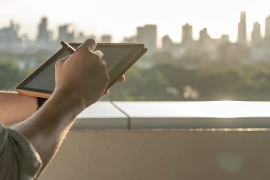 Hands holding tablet building background in the morning.