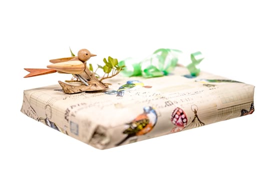 Bright gift box decorated with a wooden bird and bow isolated on white