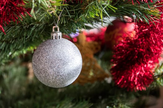 silver bauble ornament hanging on christmas tree. Beautiful close up holiday photo. .