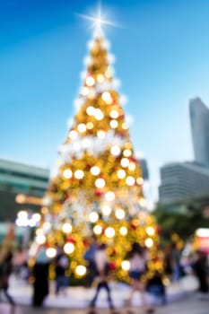 Conceptual defocused abstract decorated Christmas Tree and crowd of people on city street at night