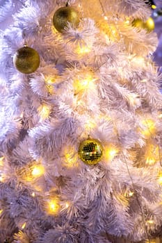 Conceptual image of decorated outdoor white Christmas tree with colorful lights and ornaments