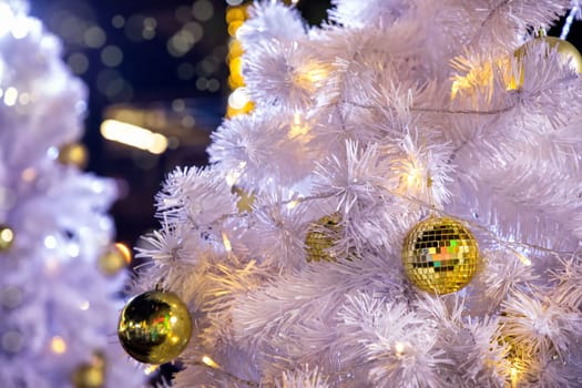 Conceptual image of decorated outdoor white Christmas tree with colorful lights and ornaments