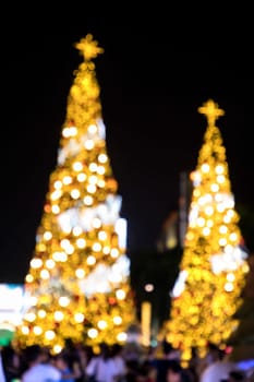 Conceptual defocused abstract decorated Christmas Tree and crowd of people on city street at night