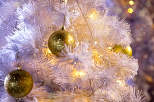 Conceptual image of decorated outdoor white Christmas tree with colorful lights and ornaments
