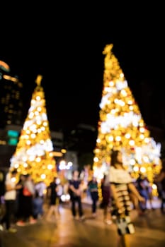 Conceptual defocused abstract decorated Christmas Tree and crowd of people on city street at night