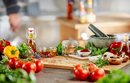 Fresh culinary herbs, spices and salad ingredients with a stone pestle and mortar on a counter in a kitchen during preparation of the dinner