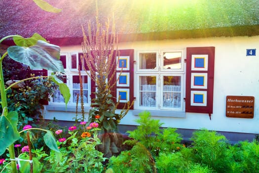 Traditional thatched roof house on the Baltic Sea with caption on the house wall in German - Hochwwasser on 18 November 1872..Lens flare desirable. Intentional blur.