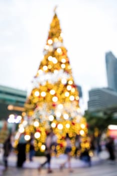 Conceptual defocused abstract decorated Christmas Tree and crowd of people on city street at night