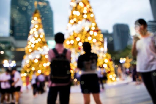 Conceptual defocused Christmas decoration and crowd of people on city street at night