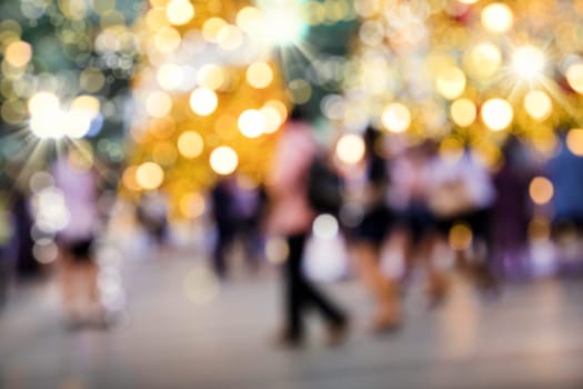Conceptual defocused Christmas decoration and crowd of people on city street at night.