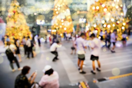 Conceptual defocused Christmas decoration and crowd of people on city street at night