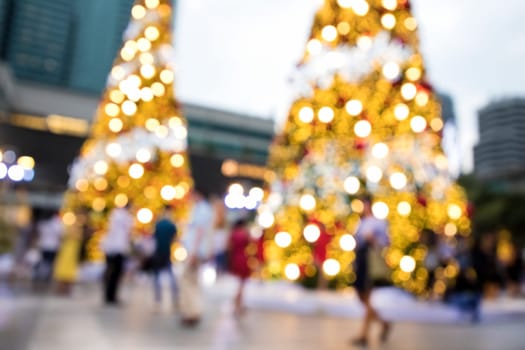 Conceptual defocused Christmas decoration and crowd of people on city street at night