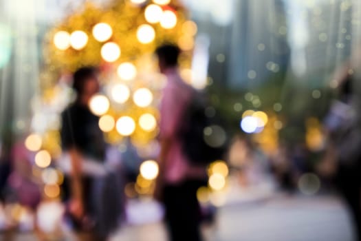 Conceptual defocused Christmas decoration and crowd of people on city street at night