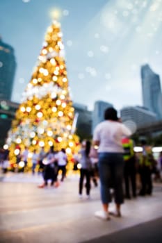 Conceptual defocused abstract decorated Christmas Tree and crowd of people on city street at night