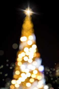 Conceptual background image of defocused abstract Christmas Tree on city street at night