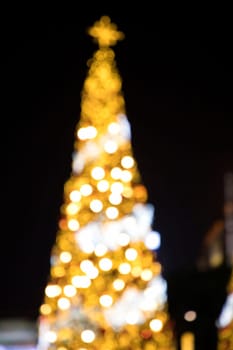 Conceptual background image of defocused abstract Christmas Tree on city street at night