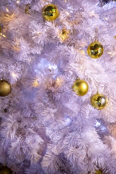 Conceptual image of decorated outdoor white Christmas tree with colorful lights and ornaments