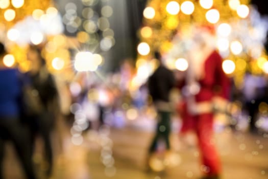 Conceptual defocused Christmas decoration and crowd of people on city street at night