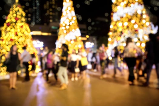 Conceptual defocused Christmas decoration and crowd of people on city street at night