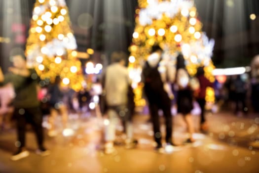 Conceptual defocused Christmas decoration and crowd of people on city street at night