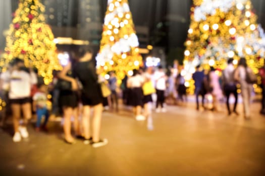 Conceptual defocused Christmas decoration and crowd of people on city street at night