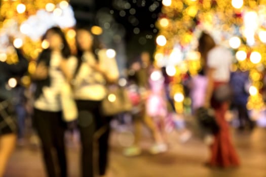 Conceptual defocused Christmas decoration and crowd of people on city street at night