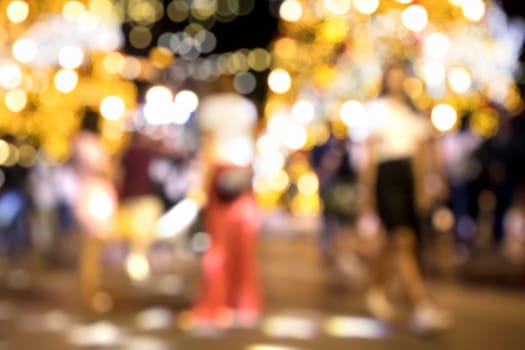 Conceptual defocused Christmas decoration and crowd of people on city street at night