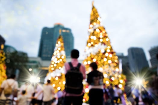 Conceptual defocused abstract decorated Christmas Tree and crowd of people on city street at night