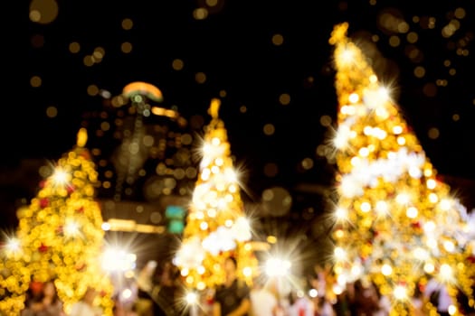 Conceptual defocused abstract decorated Christmas Tree and crowd of people on city street at night