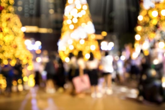 Conceptual defocused Christmas decoration and crowd of people on city street at night