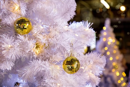 Conceptual image of decorated outdoor white Christmas tree with colorful lights and ornaments