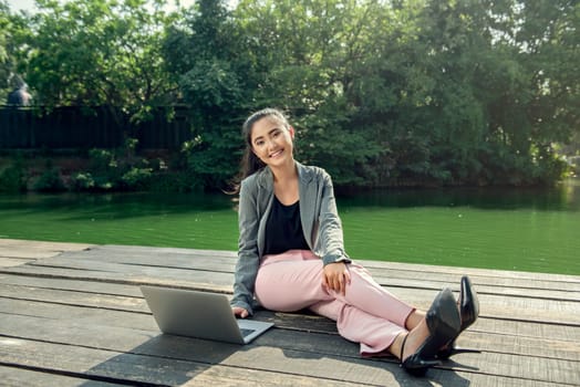 Pretty asian businesswoman using laptop while relaxing at outdoor