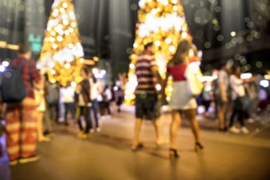 Conceptual defocused Christmas decoration and crowd of people on city street at night