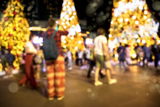 Conceptual defocused Christmas decoration and crowd of people on city street at night