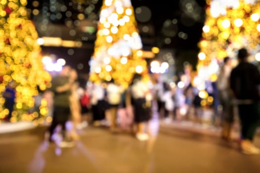 Conceptual defocused Christmas decoration and crowd of people on city street at night