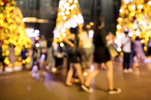 Conceptual defocused Christmas decoration and crowd of people on city street at night