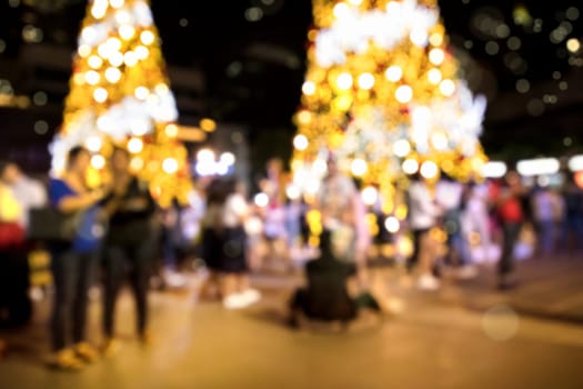 Conceptual defocused Christmas decoration and crowd of people on city street at night
