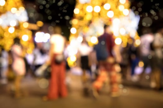 Conceptual defocused Christmas decoration and crowd of people on city street at night