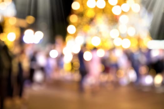 Conceptual defocused Christmas decoration and crowd of people on city street at night