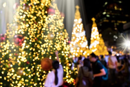 Conceptual defocused abstract decorated Christmas Tree and crowd of people on city street at night