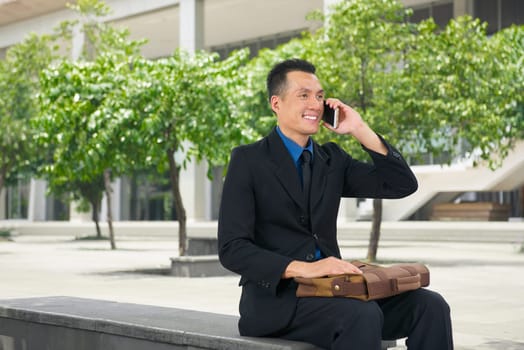 Handsome asian businessman talking on his cell phone at outdoor