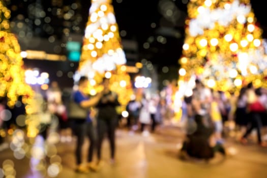 Conceptual defocused Christmas decoration and crowd of people on city street at night