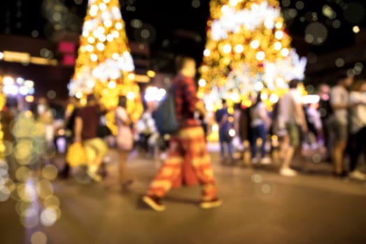 Conceptual defocused Christmas decoration and crowd of people on city street at night
