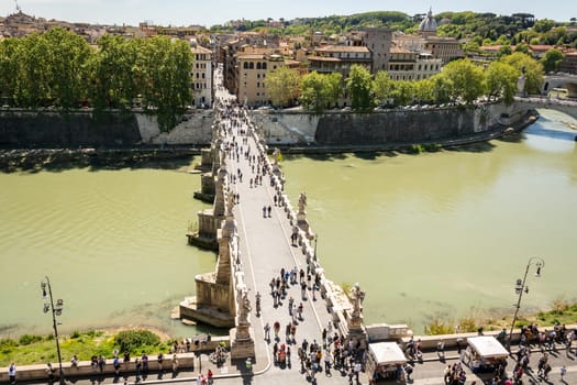 Rome, Italy, April 17th 2017: people walking on the Sant'Angelo bridge along the River Tiber in Rome. The bridge was built by Emperor Hadrian in 134 to attach to the left bank of the river his mausoleum