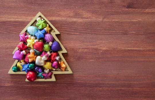 Little christmas tree with colorful baubles on wooden background