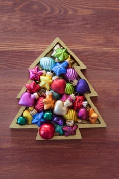 Little christmas tree with colorful baubles on wooden background