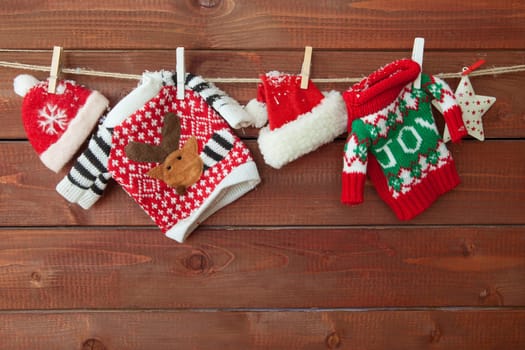 Little knitted christmas pullovers on a wooden background
