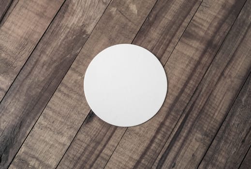 Blank white beer coaster on wooden background. Responsive design mockup. Flat lay.