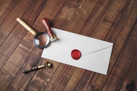 Vintage envelope and stationery: wax seal, magnifier and spoon on wooden background. Responsive design mockup.